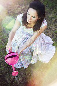 春天里浪漫的年轻女人用粉红色的淋浴浇水