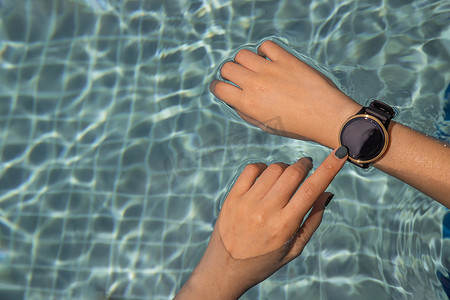 女性在游泳池用手与智能手表