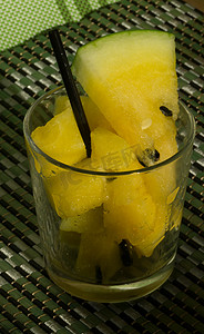 玻璃杯中的黄色西瓜，上面有切片和楔子