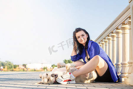 宠物狗玩耍摄影照片_年轻快乐的女人在公园里和她的狗玩耍