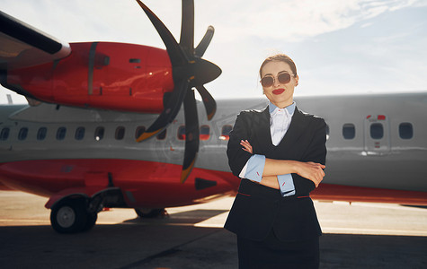 穿着正式黑色衣服的年轻空姐站在飞机附近的户外
