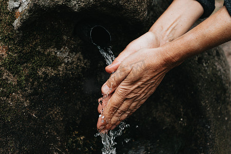文艺风字体摄影照片_老妇人用天然水源字体洗手近手
