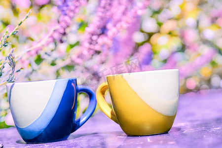 粉红色花卉背景中的黄色和蓝色咖啡茶杯