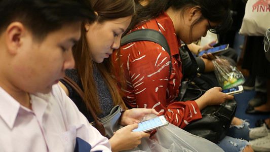 2018网络摄影照片_泰国曼谷-2018 年 12 月 18 日：泰国曼谷 BTS 轻轨站的乘客，每个人在等待 BTS 轻轨时都低头看着智能手机