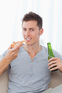 八一手绘摄影照片_一个微笑的男人，一手拿着披萨，一手拿着啤酒