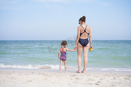 母女一起海滩后视镜 无法辨认的白种女人小女孩泳装站在海边后面。
