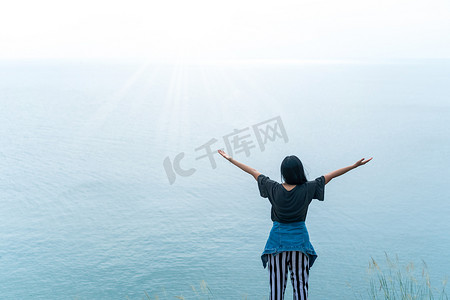 女人举起手来迎接蓝天的天空自由概念。