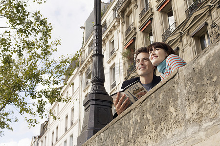 一对微笑的夫妇带着指南从桥上看的低角度视图