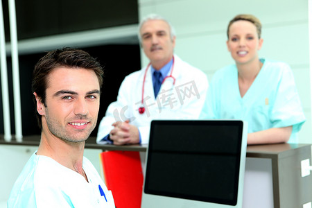 医生和护士围着一台空白屏幕的电脑