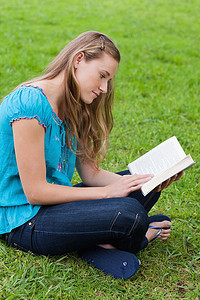 严肃的小女孩坐在公园里看书