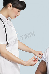 背景鼠年摄影照片_女护士在浅蓝色背景下给病人的手臂注射