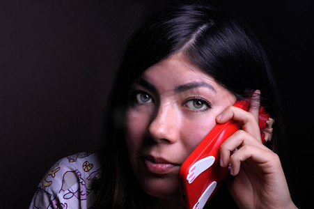 手木机壳摄影照片_绿眼睛的褐发美女用红色手机壳通话