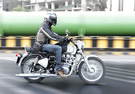 摩托车背景摄影照片_乘坐通过工业区的摩托车骑士