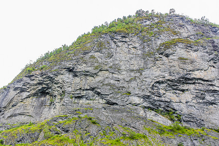 大岩石悬崖纹理与树木在挪威。