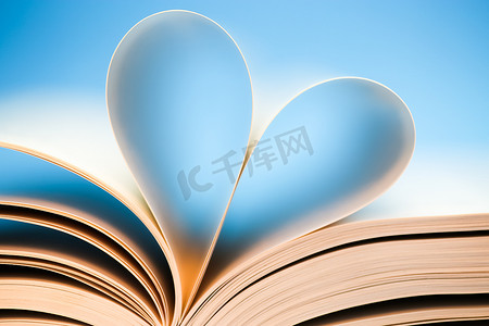 心脏蓝色背景摄影照片_在蓝色背景的书页，由书形成的发光的心脏