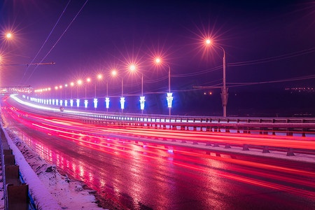 冬夜在桥上行驶的汽车的前灯痕迹。