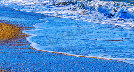 海水的特写影响沙滩上的沙子，海浪平静地流沙，放松的景色