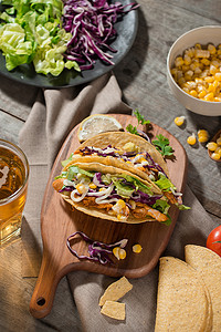 传统的墨西哥炸玉米饼，木桌上有鸡肉和蔬菜。