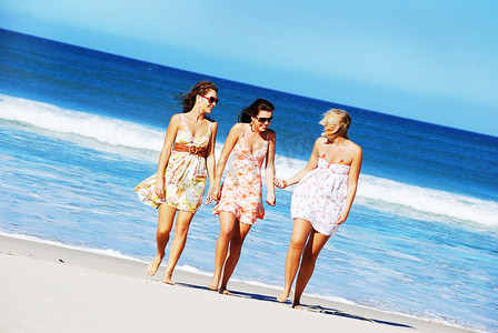夏日玩乐摄影照片_三名年轻女子在夏日的沙滩上玩乐