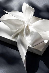 黑色背景中带丝带和蝴蝶结的豪华假日白色礼盒、豪华婚礼或生日礼物