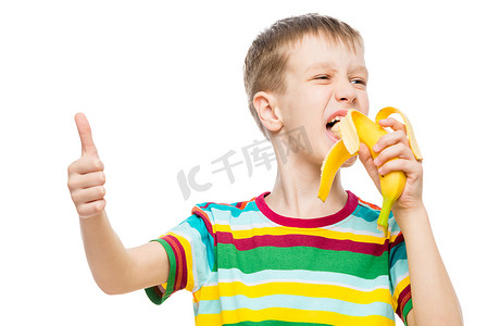吃美味的食物摄影照片_快乐的男孩在白色背景下吃美味的香蕉，肖像是 iso