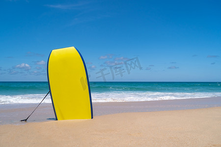 在阳光和蓝天的夏日海滩沙滩上的小冲浪板。