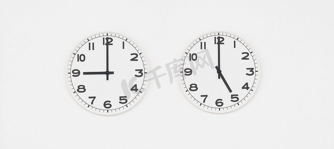 时钟摄影照片_黑色指针的白色时钟显示九点到五点