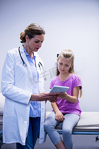 医疗报告服务摄影照片_医生用数字平板电脑向病人展示医疗报告