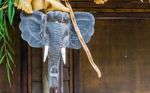 挂在木杆上的大象头雕塑，传统的非洲家居装饰