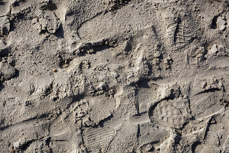 夏日阳光明媚的黄沙上有许多不同的脚印