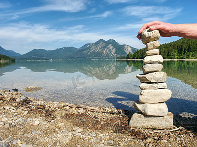 鹅卵石湖滩上的扁平石头金字塔，地平线上的群山