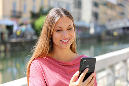在城市街道上用智能手机应用程序微笑的年轻女性视频通话的特写