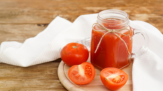 玻璃瓶中的番茄汁和木制背景中的新鲜西红柿