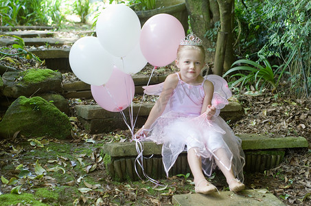 公主粉色摄影照片_小女孩在森林花园过生日时打扮成童话般的芭蕾舞公主
