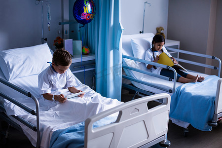数字平板电脑和书坐在床上的病人