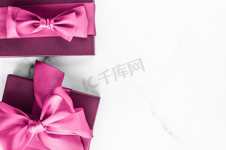 大理石背景上带丝绸蝴蝶结的粉红色礼盒、女婴淋浴礼物和奢华美容品牌的魅力时尚礼物、假日平板艺术设计