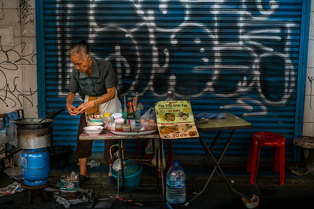 祖母一个身份不明的摊贩在她的食品摊上准备泰式炒蛋和鸡蛋。