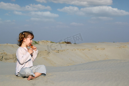 坐在沙滩上玩音乐的小女孩