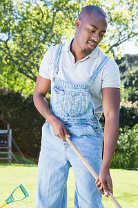 穿着工装裤的年轻人在花园里扫地