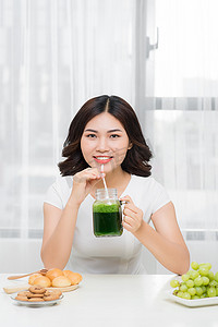 年轻的亚洲女性享受健康的素食冰沙来减肥和排毒