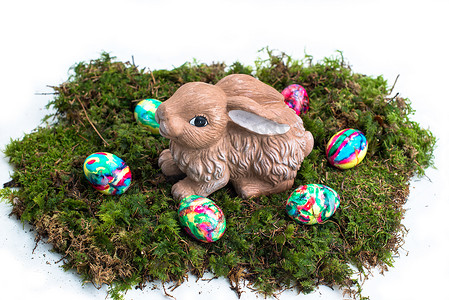 兔子黄色摄影照片_复活节装饰：苔藓上的彩蛋和兔子