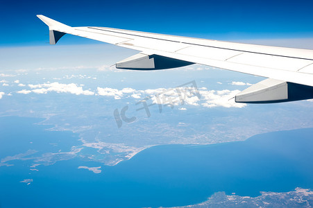 从高空多云的天空和地中海海岸线的机载飞机窗口查看。