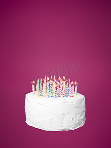 带蜡烛的蛋糕朝向粉红色背景