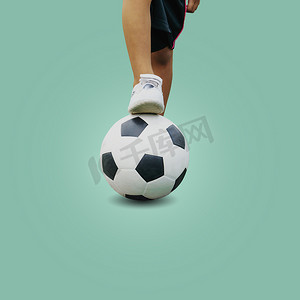 一个穿着白色运动鞋的男孩踩着足球的特写脚