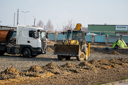 LUTSK, UKRAINE - May 10, 2020：黄色轮式装载机挖掘机和卡车在建筑工地用沙子和砾石工作。