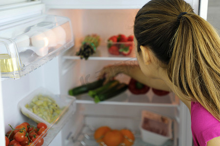 在冰箱里寻找健康食品的年轻女性的背影