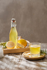 清爽夏日柠檬摄影照片_质朴的木桌上放着柠檬、生姜、迷迭香和冰的清爽夏日饮品，复制空间