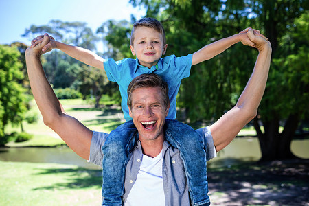 快乐的父亲在公园里把儿子扛在肩上