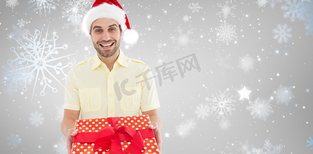 拿着礼物时戴着圣诞帽的微笑男子的合成图像