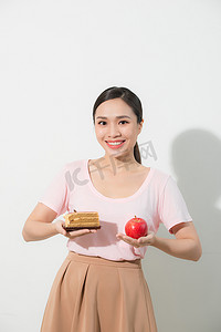 女孩一只手拿着苹果，另一只手拿着蛋糕。